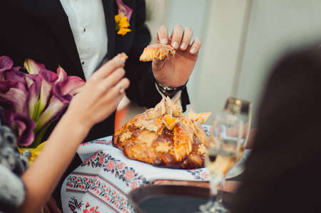 Closeup photo of bride and groom breaking traditional loafの写真素材