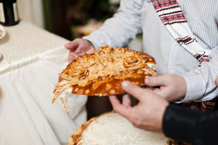 Closeup photo of bride and groom breaking traditional loafの写真素材
