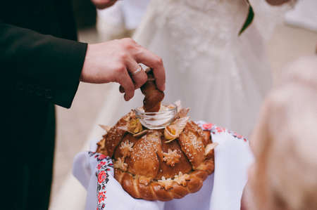 Closeup photo of bride and groom breaking traditional loafの写真素材
