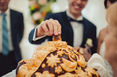 Closeup photo of bride and groom breaking traditional loafの写真素材