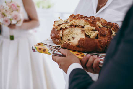 Closeup photo of bride and groom breaking traditional loafの写真素材