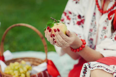 A girl in an embroidery is holding an apple in her handsの写真素材