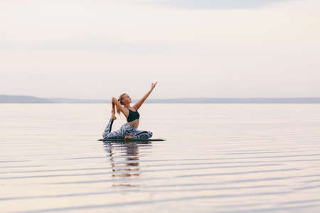 The pretty woman doing yoga at sunset outdoorsの写真素材