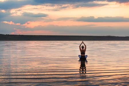 The pretty woman doing yoga at sunset outdoorsの写真素材
