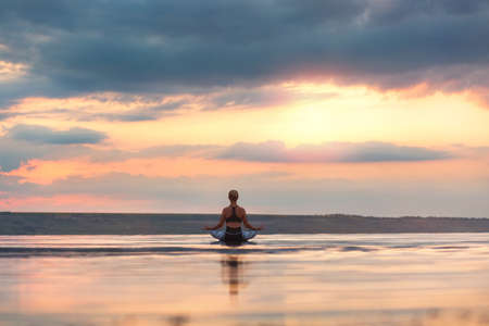 The pretty woman doing yoga at sunset outdoorsの写真素材