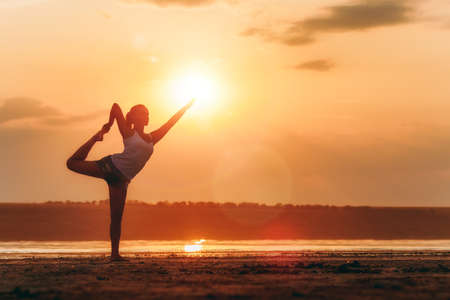 The pretty woman doing yoga at sunset outdoorsの写真素材