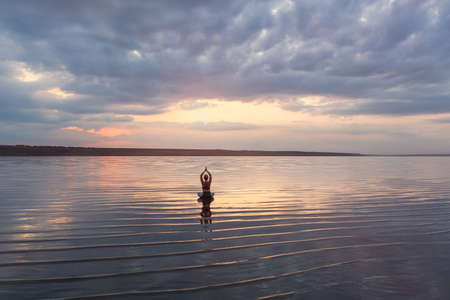 The pretty woman doing yoga at sunset outdoorsの写真素材