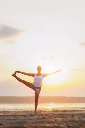 The pretty woman doing yoga at sunset outdoorsの写真素材