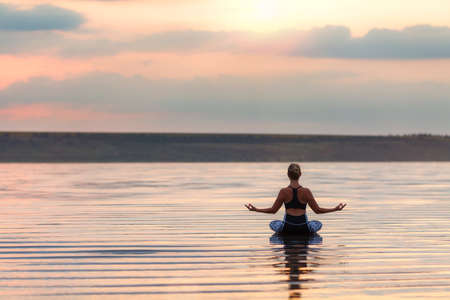 The pretty woman doing yoga at sunset outdoorsの写真素材