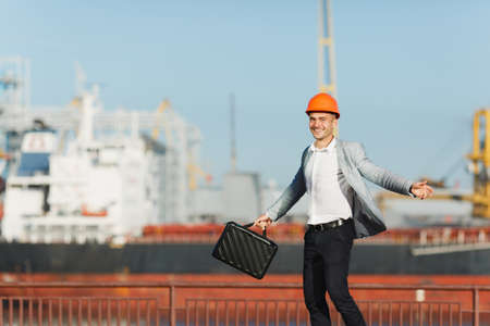 Handsome young unshaven successful business man in gray suit and protective construction orange...