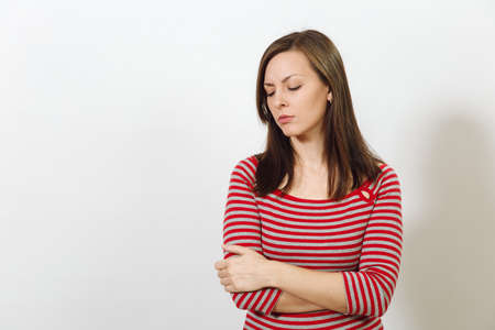 The pretty European young worried and pensive brown-haired woman with healthy clean skin, dressed in casual red and grey clothes lost in thought and conjectures, on a white background. Emotions concept.の写真素材