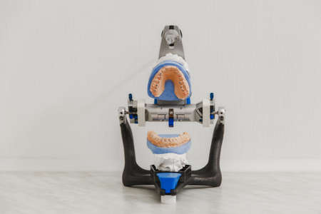 The articulator in a dental lab with open mold or artificial denture in dental lab on white...