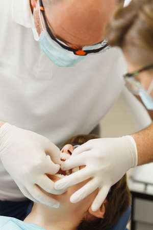 Close up process of preparing and installing dental ceramic crown. Male professional dentist helps...
