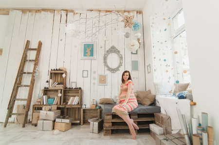 Happy pregnant young brunette woman in striped long dress with big belly in decor room, tummy, teddy bear. Pregnancy, parenthood, family, motherhood, parents, children, people and expectation conceptの写真素材