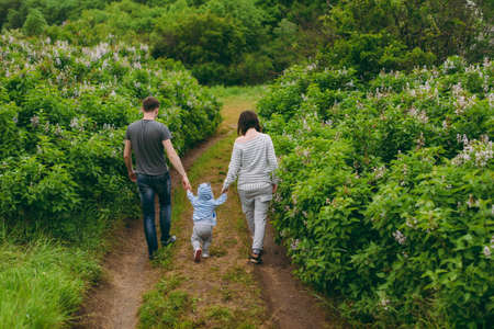 Man, woman walking on nature bush background holding hands little cute child baby boy. Mother,...