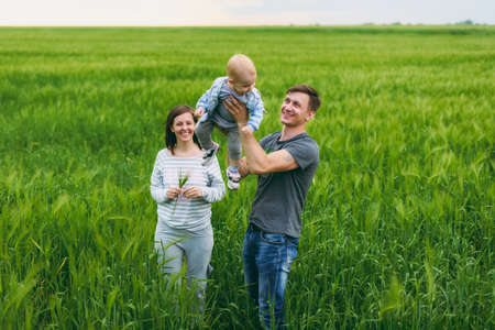 Joyful fun man, woman walking on nature background hugging, playing with little cute child baby boy. Mother, father, little kid son. Parenthood, family day 15 of may, love, parents, children conceptの写真素材