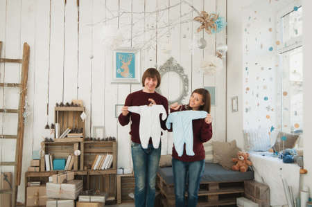 Happy pregnant young woman with big belly tummy, man in decor room. Couple with kid clothes. Wife, husband. Pregnancy, parenthood, family, motherhood, parents, children people and expectation conceptの写真素材