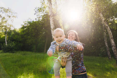 Young joyful woman walking on nature park background holding on hands, circling little cute child baby boy. Mother, little kid son. Parenthood, family day 15 of may, love, parents, children conceptの写真素材