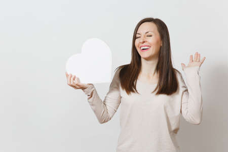 Pretty young cheerful woman holding big white heart in hands isolated on white background. Copy space for advertisement. With place for text. St. Valentine's Day or International Women's Day conceptの写真素材