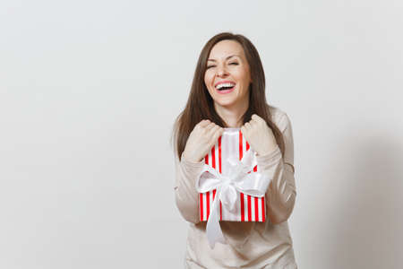 Effective woman hugging red striped present box with ribbon, bow isolated on white background. For advertisement. St. Valentine's Day, International Women's Day, Christmas, birthday, holiday conceptの写真素材