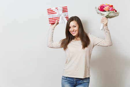 Young pretty woman holding bouquet of beautiful roses flowers, present box with gift isolated on white background. Copy space for advertisement. St Valentines Day or International Women's Day conceptの写真素材