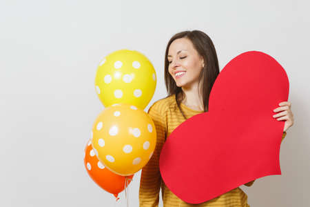 Young woman holding big red heart, yellow orange balloons isolated on white background. Copy space for advertisement. With place for text. St. Valentine's Day or International Women's Day conceptの写真素材