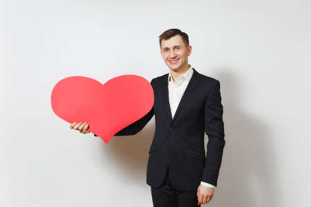 Young handsome man in suit holding big red heart isolated on white background. Copy space, advertisement. Place for text. St. Valentine's Day, International Women's Day, birthday, holiday conceptの写真素材