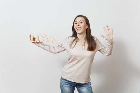 Beautiful young brunette fun smiling woman in light casual clothes holding wooden word love on white background. Copy space for advertisement. St. Valentine's Day or International Women's Day conceptの写真素材