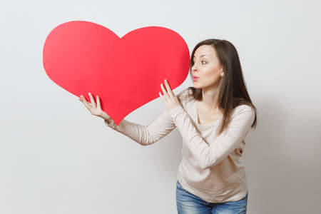 Beautiful young smiling woman holding big red heart in hands isolated on white background. Copy space for advertisement. With place for text. St. Valentine's Day or International Women's Day conceptの写真素材