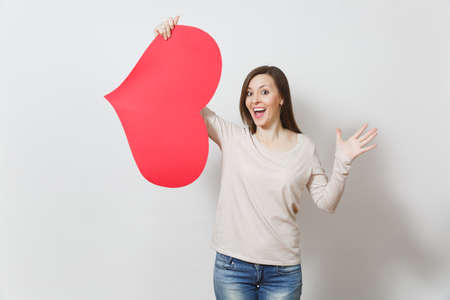 Attractive young smiling woman holding big red heart in hands isolated on white background. Copy space for advertisement. With place for text. St. Valentine's Day or International Women's Day conceptの写真素材