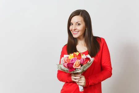 Young smiling woman in red clothes holding bouquet of beautiful roses flowers isolated on white background. Copy space for advertisement. St. Valentine's Day or International Women's Day conceptの写真素材