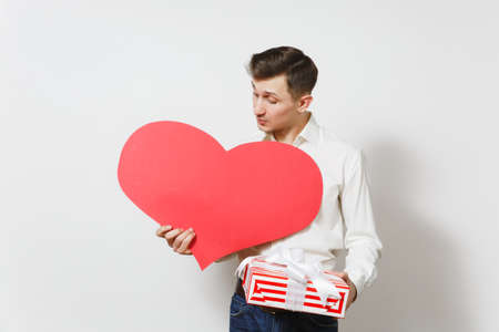 Young handsome smiling man in shirt holding red present box with gift isolated on white background. Copy space for advertisement. St. Valentines Day, International Womens Day birthday holiday conceptの写真素材
