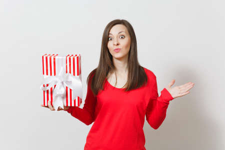Woman spreading hands, holding red striped present box with ribbon isolated on white background. For advertisement. St. Valentines Day, International Women's Day, Christmas, birthday, holiday conceptの写真素材