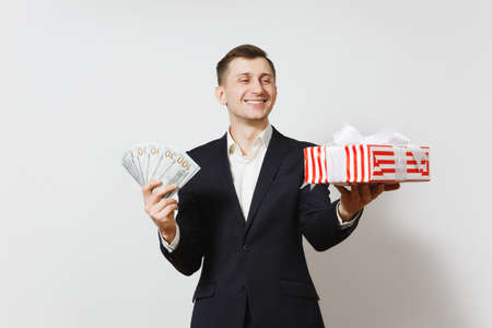 Young handsome man in suit holding red present box with gift, bundle of cash money dollars isolated on white background. St. Valentine's Day, International Women's Day, birthday holiday conceptの写真素材