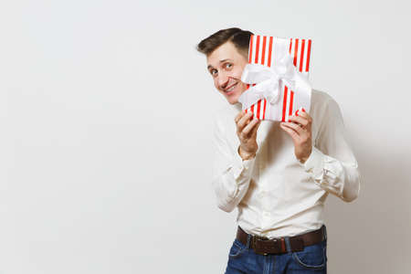 Young handsome smiling man in shirt holding red present box with gift isolated on white background. Copy space for advertisement. St. Valentines Day, International Womens Day birthday holiday conceptの写真素材