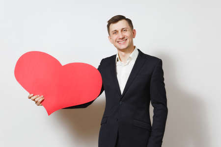 Young handsome man in suit holding big red heart isolated on white background. Copy space, advertisement. Place for text. St. Valentine's Day, International Women's Day, birthday, holiday conceptの写真素材