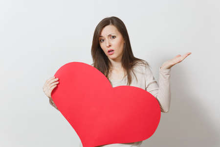 Sad upset lamentable woman holding big red heart in hands isolated on white background. Copy space for advertisement. With place for text. St. Valentine's Day or International Women's Day conceptの写真素材