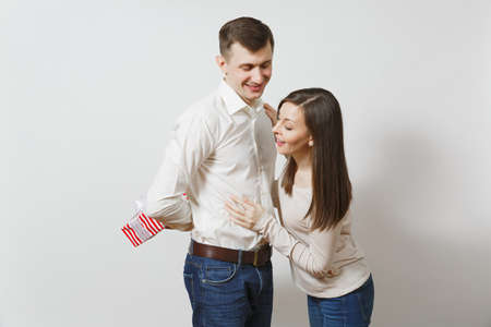 Cute fun couple in love. Woman looking behind man who hiding behind him red present box with gift isolated on white background. St. Valentine's Day, International Women's Day birthday holiday conceptの写真素材