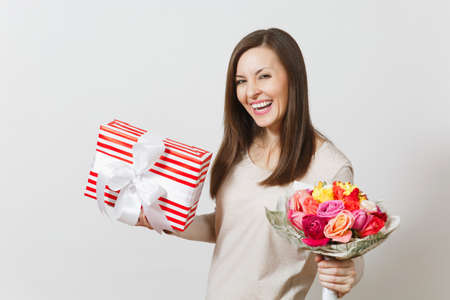 Young pretty woman holding bouquet of beautiful roses flowers, present box with gift isolated on white background. Copy space for advertisement. St Valentines Day or International Women's Day conceptの写真素材