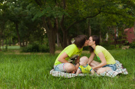 Joyful fun man, woman walking on picnic kissing, hugging, playing with little cute child baby boy. Mother, father, little kid son. Parenthood, family day 15 of may, love, parents, children conceptの写真素材