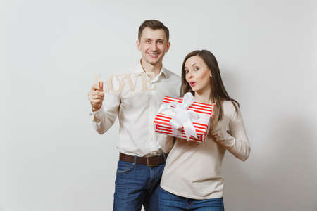 Cute couple in love. Man, woman with wooden word Love, present box with gift isolated on white background. For advertisement. St. Valentine's Day, International Women's Day, birthday, holiday conceptの写真素材