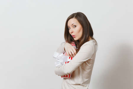 Fun cheerful woman hugging red striped present box with ribbon, bow isolated on white background. For advertisement. St. Valentine's Day, International Women's Day, Christmas birthday holiday conceptの写真素材