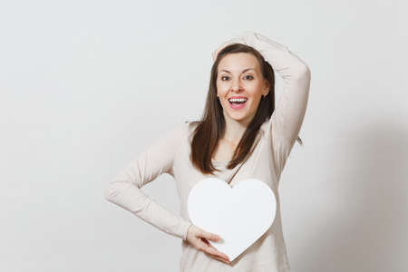 Pretty young cheerful woman holding big white heart in hands isolated on white background. Copy space for advertisement. With place for text. St. Valentine's Day or International Women's Day conceptの写真素材
