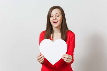 Pretty woman in red clothes holding big white heart in hands isolated on white background. Copy space for advertisement. With place for text. St. Valentine's Day or International Women's Day conceptの写真素材