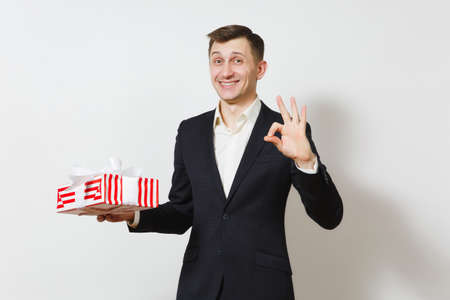 Young handsome smiling man in suit holding red present box with gift isolated on white background. Copy space for advertisement. St. Valentine's Day International Women's Day birthday holiday conceptの写真素材