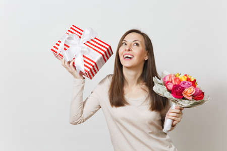 Young pretty woman holding bouquet of beautiful roses flowers, present box with gift isolated on white background. Copy space for advertisement. St Valentines Day or International Women's Day conceptの写真素材