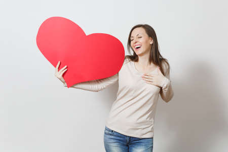 Pretty fun young smiling woman holding big red heart in hands isolated on white background. Copy space for advertisement. With place for text. St. Valentine's Day or International Women's Day conceptの写真素材