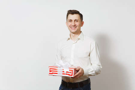 Young handsome smiling man in shirt holding red present box with gift isolated on white background. Copy space for advertisement. St. Valentines Day, International Womens Day birthday holiday conceptの写真素材