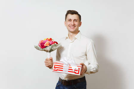 Young handsome man in shirt holding bouquet of beautiful roses flowers, red present box with gift isolated on white background. St. Valentine's Day, International Women's Day birthday holiday conceptの写真素材