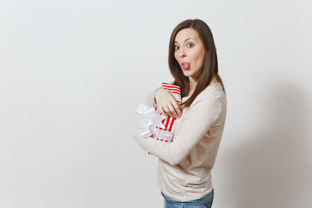 Fun cheerful woman hugging red striped present box with ribbon, bow isolated on white background. For advertisement. St. Valentine's Day, International Women's Day, Christmas birthday holiday conceptの写真素材